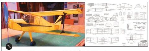 Photograph of a yellow model biplane beside a sheet of Wanderer plans
