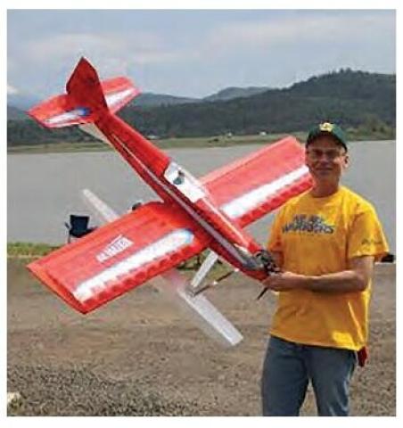 Bruce Tharpe standing beside a red model airplane