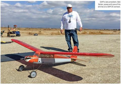 Bob Galler standing behind a large red model airplane at a SAM 26 contest.