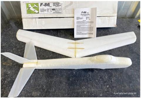 Partially built foam glider kit with wings, fuselage, tail, and instruction sheet.