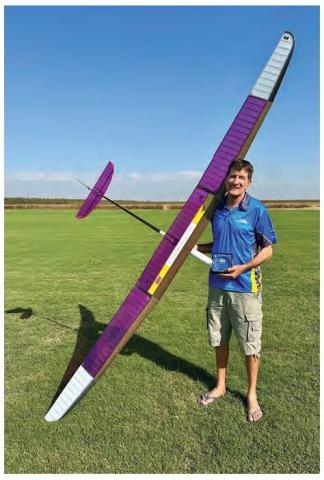 Joe Nave standing outdoors beside a large purple-and-white RC glider