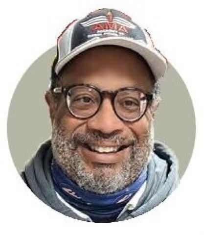 Portrait of Randy Gibson wearing glasses, a cap, and a scarf.