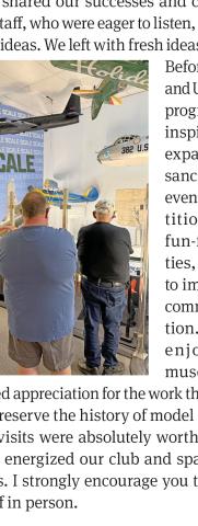 People viewing exhibits in a museum hangar with model aircraft on display