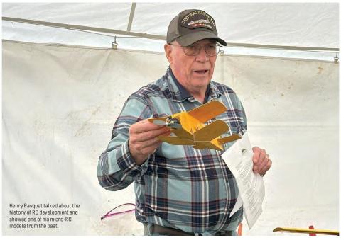 Henry Pasquet holding a small micro-RC airplane and a sheet of paper indoors.