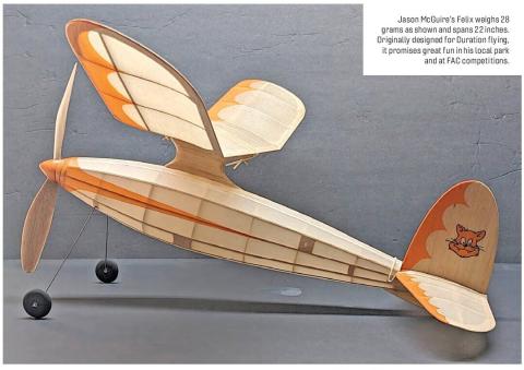 Small wooden model airplane with orange-and-cream wings and tail, displayed on a tabletop.