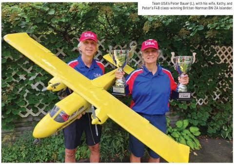 Peter Bauer and his wife Kathy hold trophies beside their yellow Britten-Norman BN-2A Islander model.