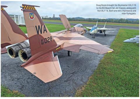 Several large radio-controlled military-style jets parked beside a runway, including a prominent F-15 model.