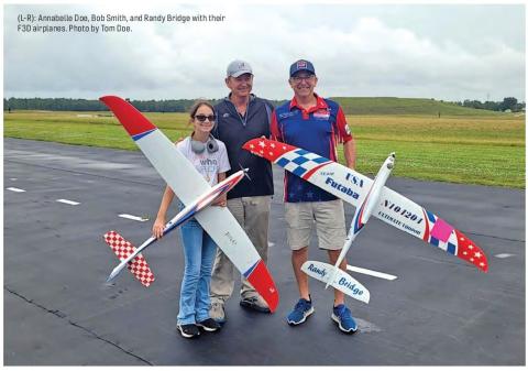 Three people standing on an airfield with F3D model airplanes.