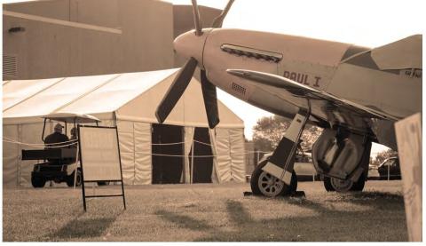 Aircraft displayed outdoors beside a tent and golf cart.