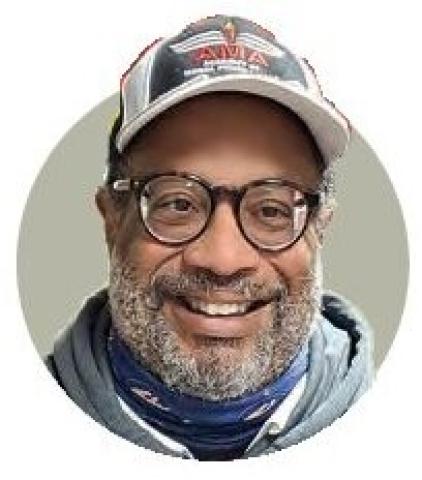 Portrait of Randy Gibson wearing glasses, a cap, and scarf.