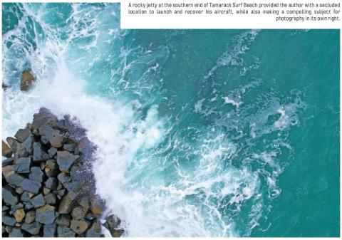 Aerial photograph of waves breaking against a rocky jetty.