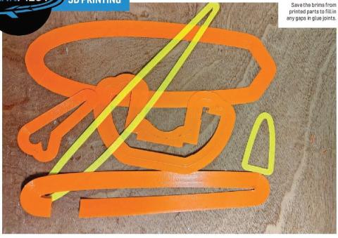 Orange and yellow 3D-printed brim pieces arranged on a wooden surface.