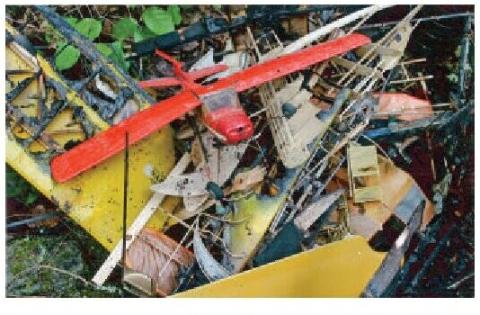 Red model airplane and other aircraft parts in the burned remains of a workshop