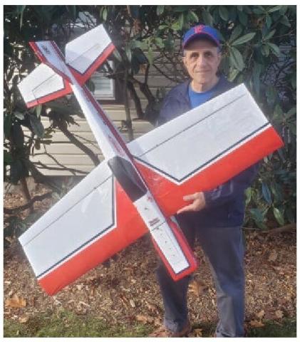 Mark Sirianni holding a red-and-white model airplane outdoors.